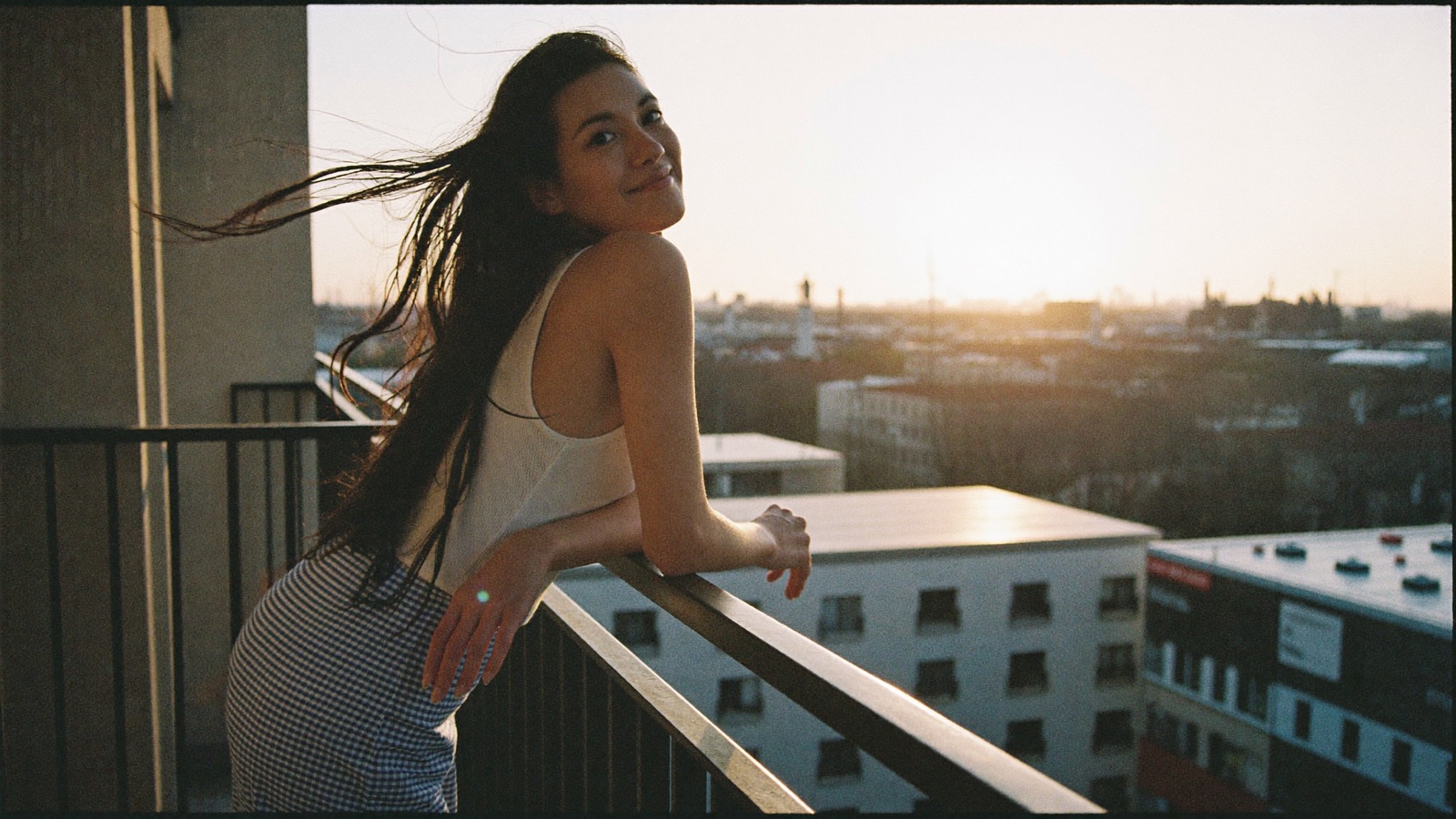 A creator leaning on a city balcony rail at golden hour