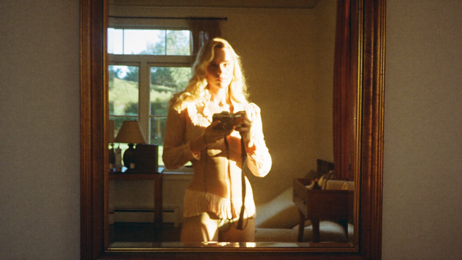 A creator taking a mirror photo in a sunlit room