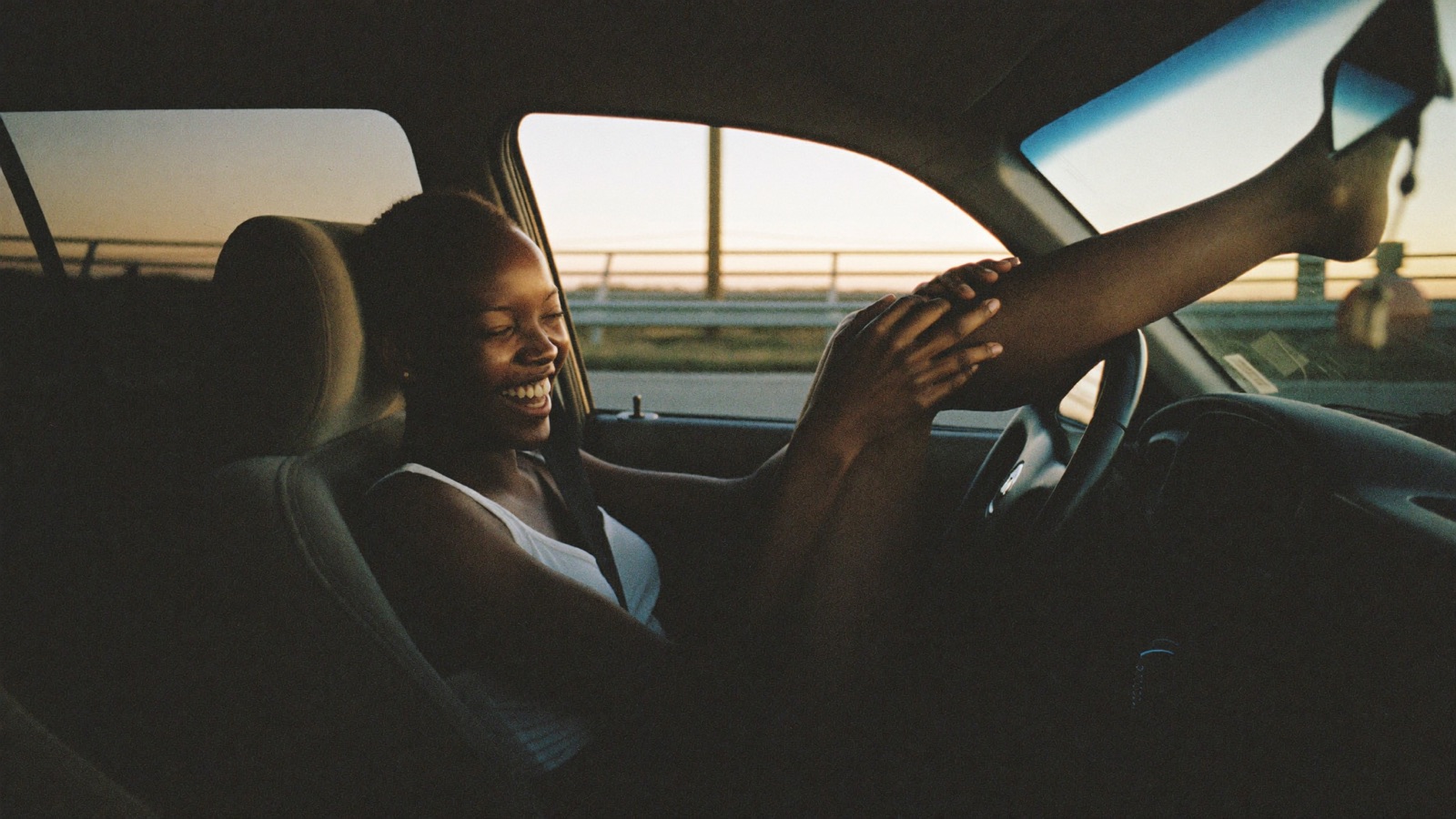 A creator laughing in a car at sunset