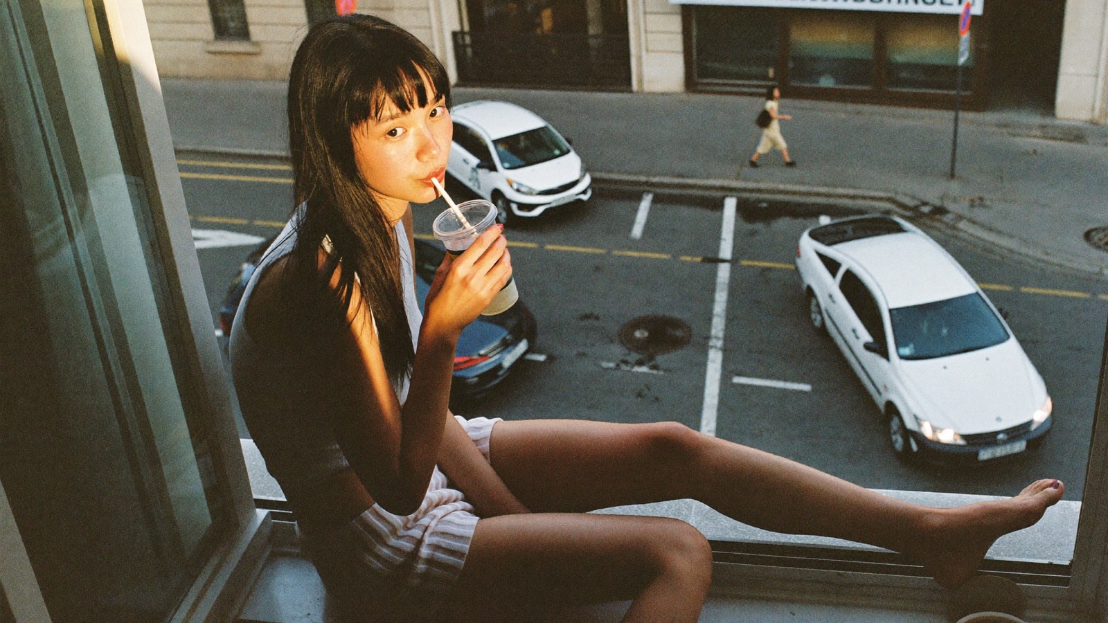 A creator sitting on a windowsill above the city at golden hour