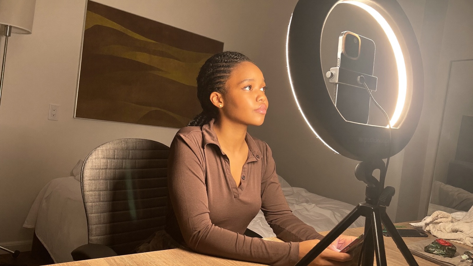A ring light with a phone mounted in the center placed in front of the model, slightly above eye level