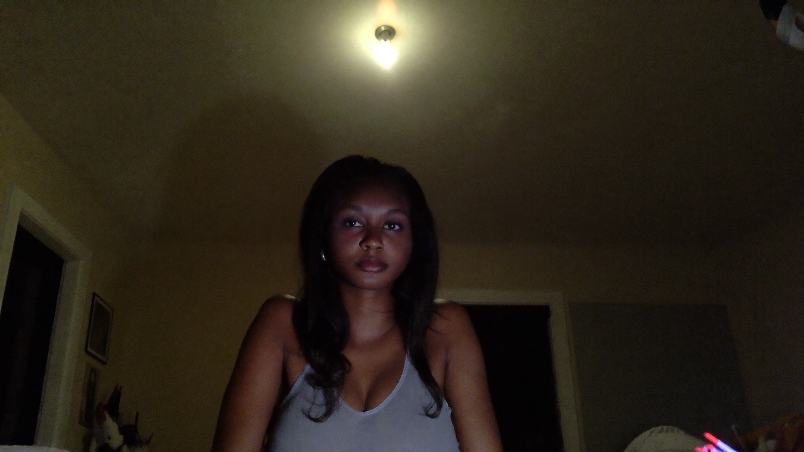 A model lit only by a single ceiling bulb, her face dim with dark shadows under her eyes