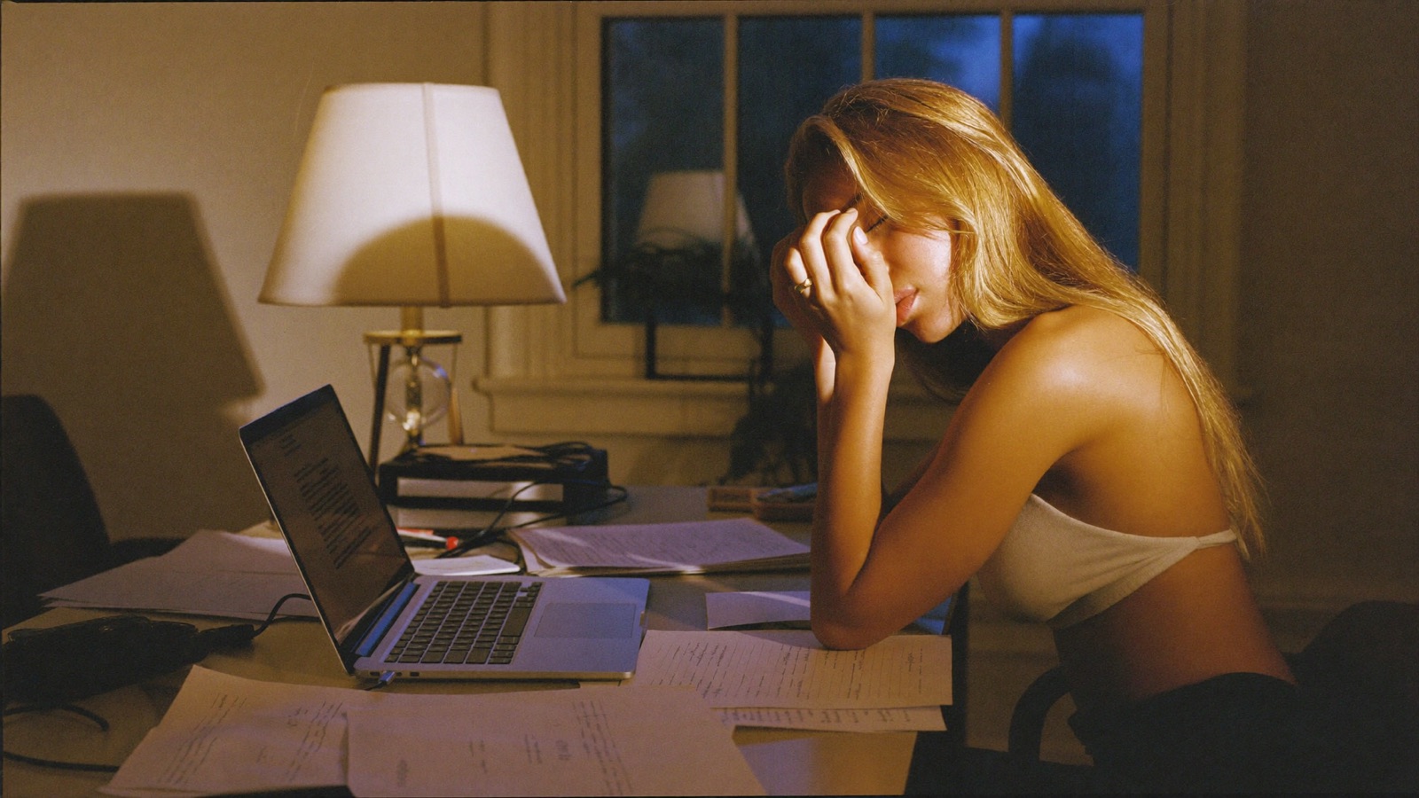 A creator working alone late at night at a cluttered desk