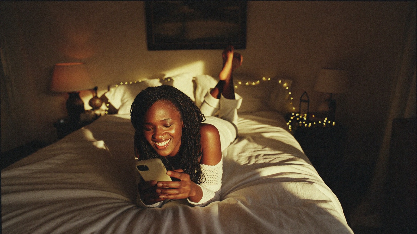 A creator smiling at her phone while messaging a fan